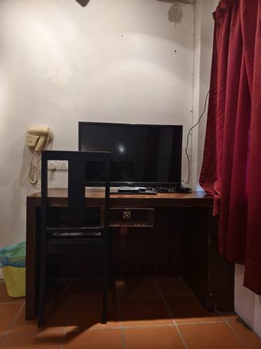 a desk with a television and a telephone in a room at Red Inn Court in George Town
