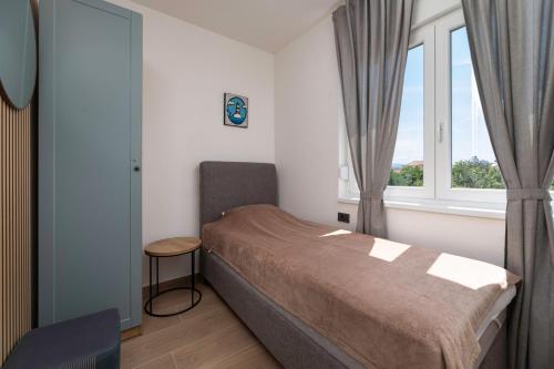 a small bedroom with a bed and a window at Apartman sa pogledom na more- Petra in Šilo