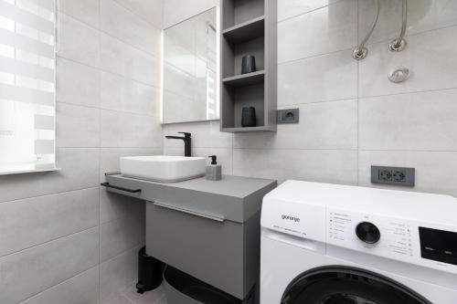 a white bathroom with a sink and a washing machine at Apartman sa pogledom na more- Petra in Šilo