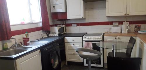 a kitchen with a sink and a table in it at Sports City Guest House in Manchester