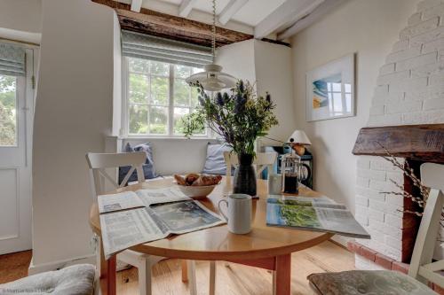 a dining room table with a vase of flowers on it at The White Cottage in Woodstock