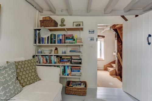 a living room with a white couch and books at The White Cottage in Woodstock