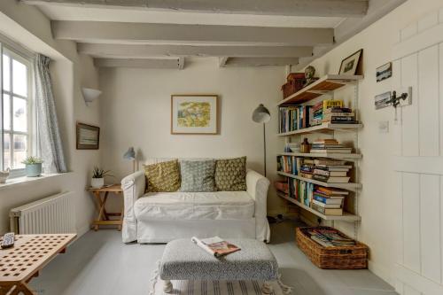 a living room with a white couch and a book shelf at The White Cottage in Woodstock
