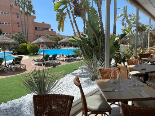 a restaurant with tables and chairs and a pool at Arena Center in Roquetas de Mar
