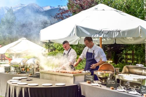 two men preparing food on a grill on a table at Kempinski Hotel Grand Arena Bansko in Bansko