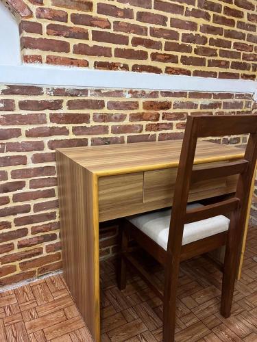 a wooden desk with a chair next to a brick wall at Pilachhen Community Homestay Thachyacha Room 2A in Pātan