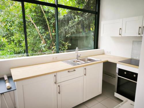 une cuisine avec des placards blancs et une grande fenêtre dans l'établissement CastelBox Nature Accès direct IntraMuros, à Avignon