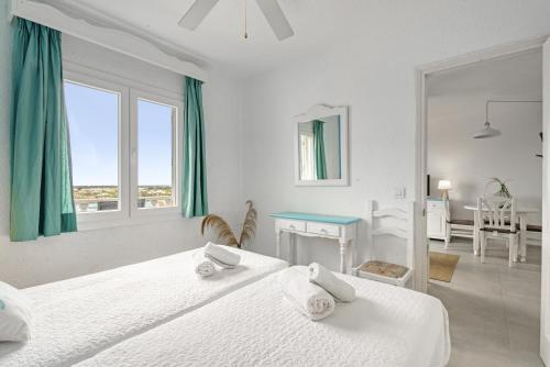 a white bedroom with two beds and a table at Apartamento 103 Castell Sol in Arenal d'en Castell