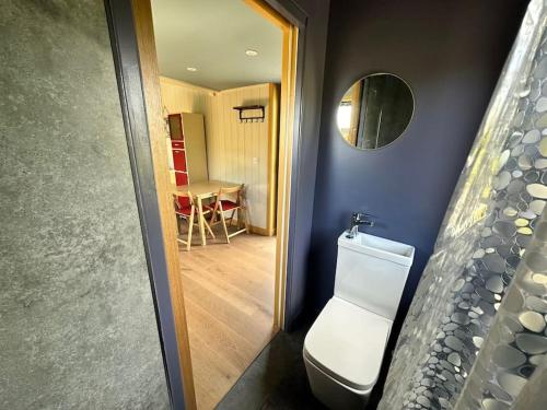 a bathroom with a toilet and a room with a table at Jura - The Rusty Hut in Craighouse