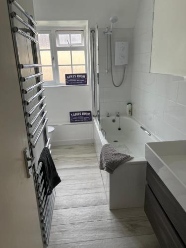 a white bathroom with a tub and a sink at Staddlestones Broadway in Broadway