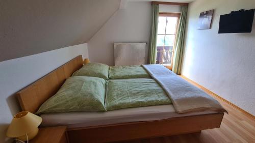 a bedroom with a bed with green sheets and a window at Waldherrhof in Aich