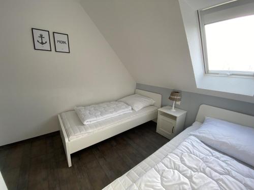 a small bedroom with two beds and a window at Haus Am Dorfteich D mit Spielplatz in Fehmarn
