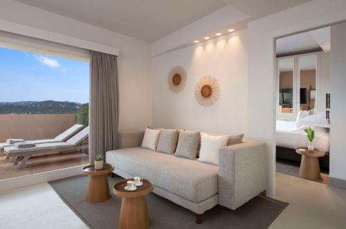 a living room with a couch and a bedroom at Baia Di Chia Resort Sardinia, Curio Collection By Hilton in Chia