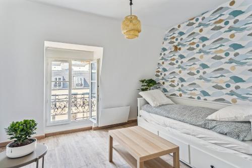 un salon avec un lit et une fenêtre dans l'établissement Charmant Studio, à Paris