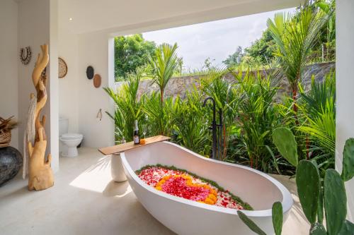 a bath tub filled with flowers in a room with a window at Villa Irrawaddy Lovina in Lovina