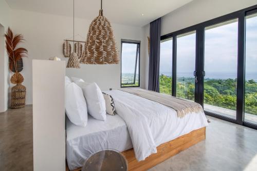 a bedroom with a large bed and large windows at Villa Irrawaddy Lovina in Lovina