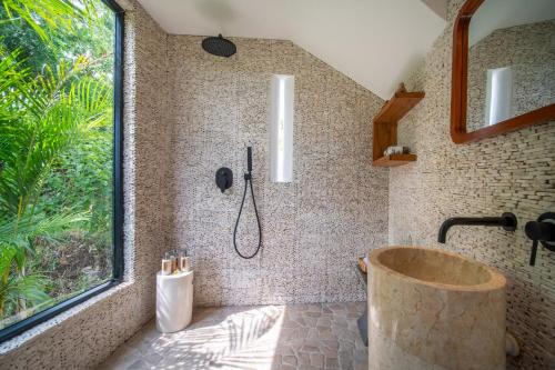 a bathroom with a tub and a window and a shower at Villa Irrawaddy Lovina in Lovina
