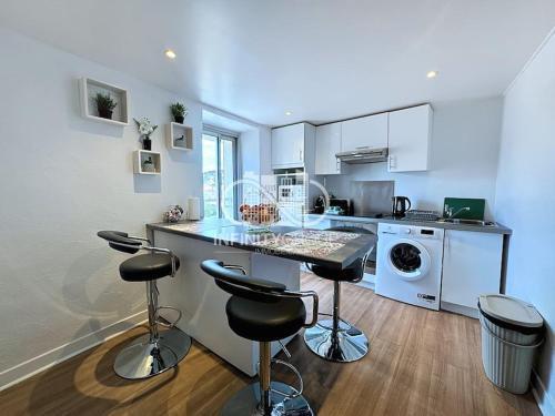une cuisine avec un comptoir et des tabourets dans une pièce dans l'établissement Grand 2p Proche Palais - Boulevard Delaup Cannes, à Cannes