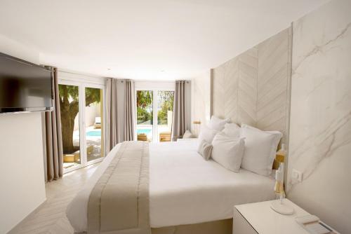 a white bedroom with a large bed and a television at Hôtel Marinca & Spa in Olmeto