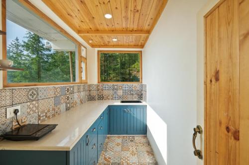 a kitchen with blue cabinets and a window at Jomotel Dayaar - An Apple Orchard Villa in Theog