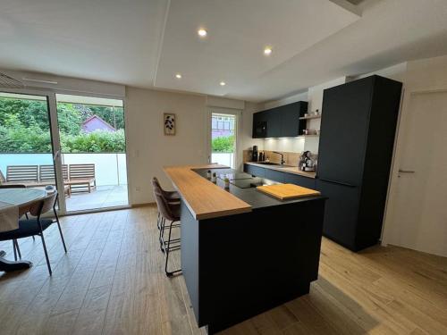 une cuisine avec un îlot noir dans une pièce avec une table dans l'établissement Au Domaine des Vignes - Appt 4 Pers avec balcon, à Barr
