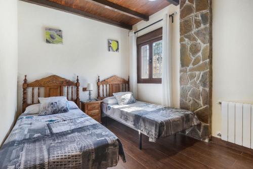 Un dormitorio con dos camas y una pared de piedra. en La Casita, en Ronda