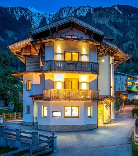 a house with a balcony in the mountains at night at Alpenresort Thanner in Mayrhofen