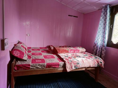 a bedroom with a bed with a pink wall at The Evergreen house kalga in Litham