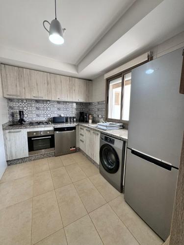 a kitchen with a refrigerator and a washer and dryer at Saidia, résidence la perla in Saidia 