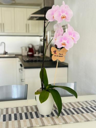 a white vase with pink flowers on a table at Bungalow Casita in Maspalomas
