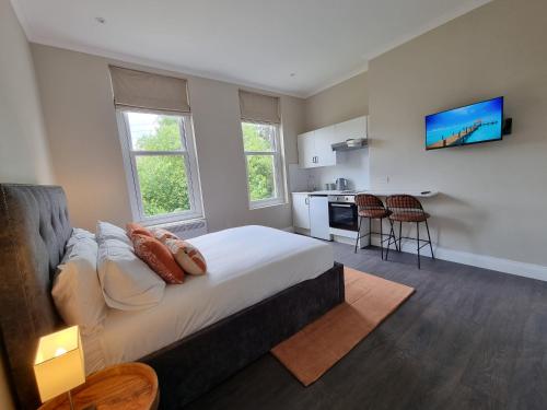 a bedroom with a large bed and a kitchen at The Ivy Apartments in Bournemouth