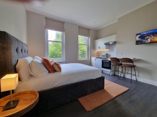 a bedroom with a large bed and a kitchen at The Ivy Apartments in Bournemouth