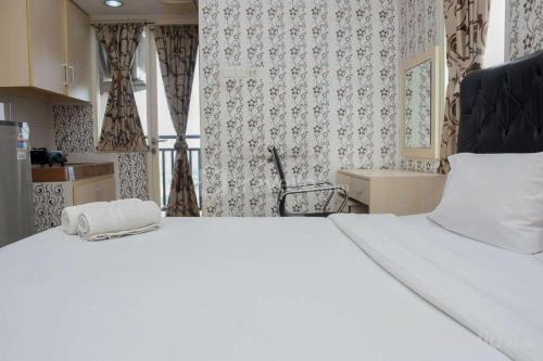 デポックにあるComfy and Tidy Studio Apartment at Margonda Residence 4 near UI By Travelioのタオルが敷かれた白いベッドのある寝室
