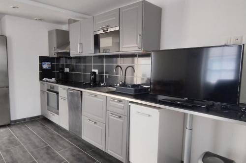 une cuisine avec une grande télévision et un comptoir dans l'établissement Charmante maison du marché de Domino, à Les Sables Vignier