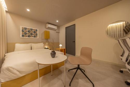 a bedroom with a bed and a table and a chair at Nomad Aank Hotel Gumi in Gumi