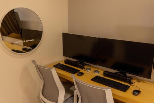 a desk with two computer monitors and a mirror at Nomad Aank Hotel Gumi in Gumi