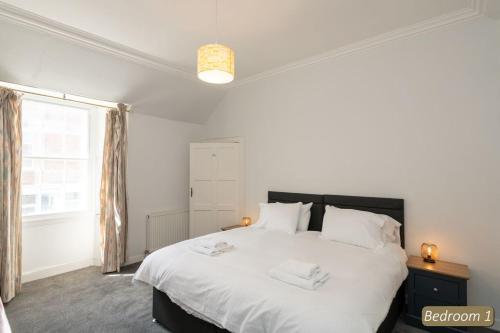 a bedroom with a large white bed and a window at Beach Court in North Berwick