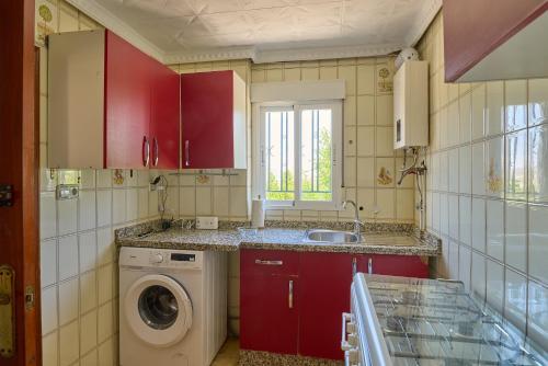- une cuisine avec des placards rouges et un lave-linge dans l'établissement Casa rural la brisa, à Baena