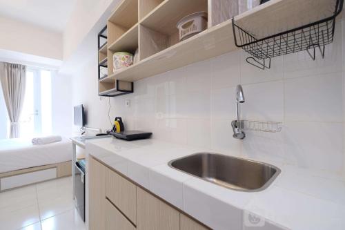 a white kitchen with a sink and a bed at Comfy and Best Choice Studio Apartment Tokyo Riverside PIK 2 By Travelio in Rawalembang