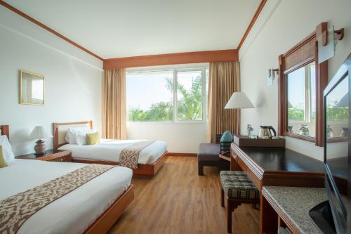 a hotel room with two beds and a desk at Centara Life Hotel Mae Sot in Mae Sot