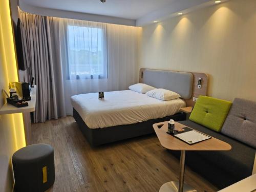 a hotel room with a bed and a couch at B&B HOTEL Deauville-Touques in Deauville