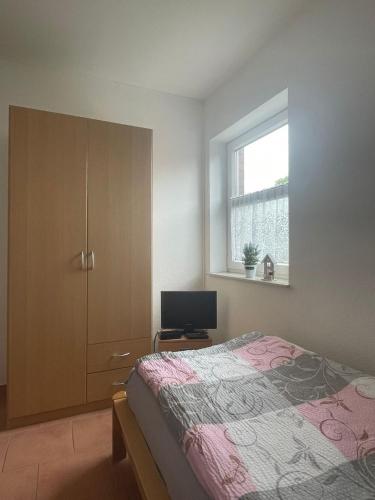 a bedroom with a bed and a cabinet and a television at Ferienwohnung Hartung in Hinte
