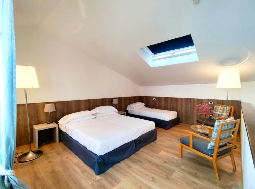 a hotel room with two beds and a chair at Albergo Del Sole in Porto Valtravaglia