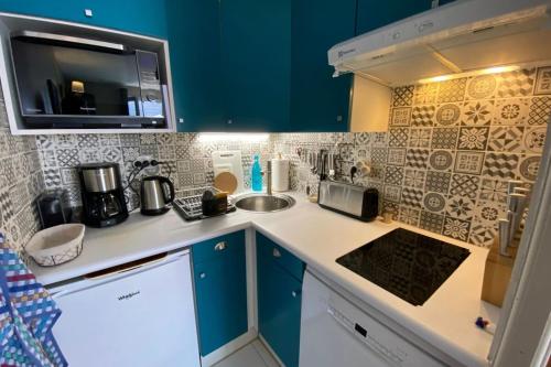 eine kleine Küche mit blauen Schränken und einer Spüle in der Unterkunft Chauveau - entre port et plage in Saint-Martin-de-Ré