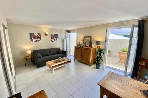 ein Wohnzimmer mit Sofa und Tisch in der Unterkunft Chauveau - entre port et plage in Saint-Martin-de-Ré