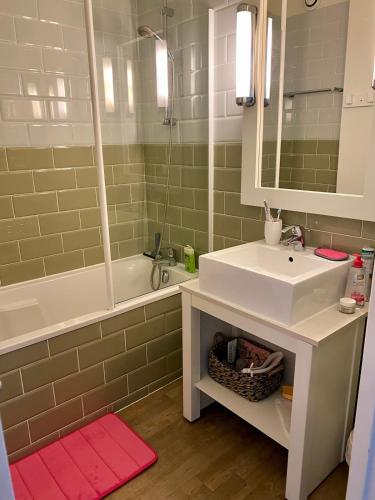 une salle de bain avec un lavabo, une baignoire et un miroir dans l'établissement Apt 4 residence in the heart of St-Martin with swimming pool and parking, à Saint-Martin-de-Ré