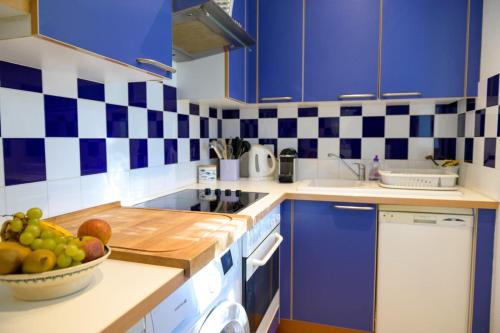 - une cuisine avec des placards bleus et un bol de fruits dans l'établissement House with large garden and terrace a stone's throw from the port, à Saint-Martin-de-Ré