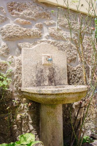 a stone sink sitting on the side of a stone wall at Casa das Fontes in Ponte da Barca