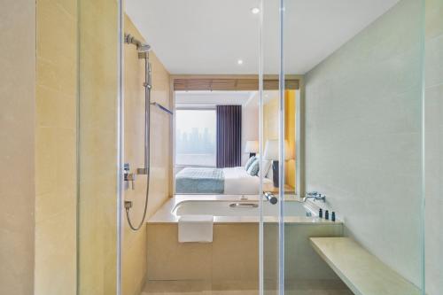 a bathroom with a shower and a sink and a bed at Marco Polo Wuhan in Wuhan