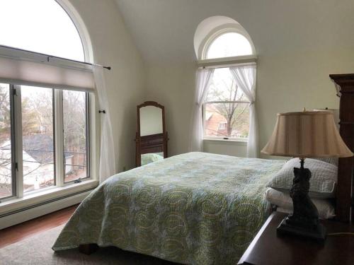 a bedroom with a bed with a lamp and two windows at idream beautiful place by the sea in Ogunquit